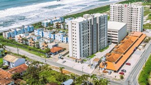 A coastal urban area with high-rise buildings, a beach, and a road. - Solarium Beach Club - Apartamento T2.205 (Itapoá)