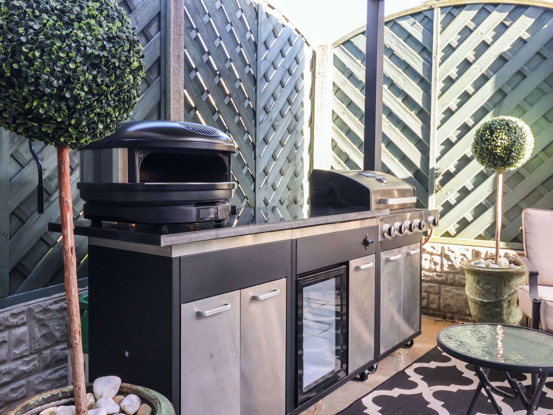 Un barbecue doté d’un four intégré, d’un petit réfrigérateur et d’une vitrine.