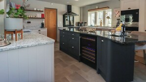 Ett modernt kök med en central köksö, inbyggd vinkyl och ett stort fönster.