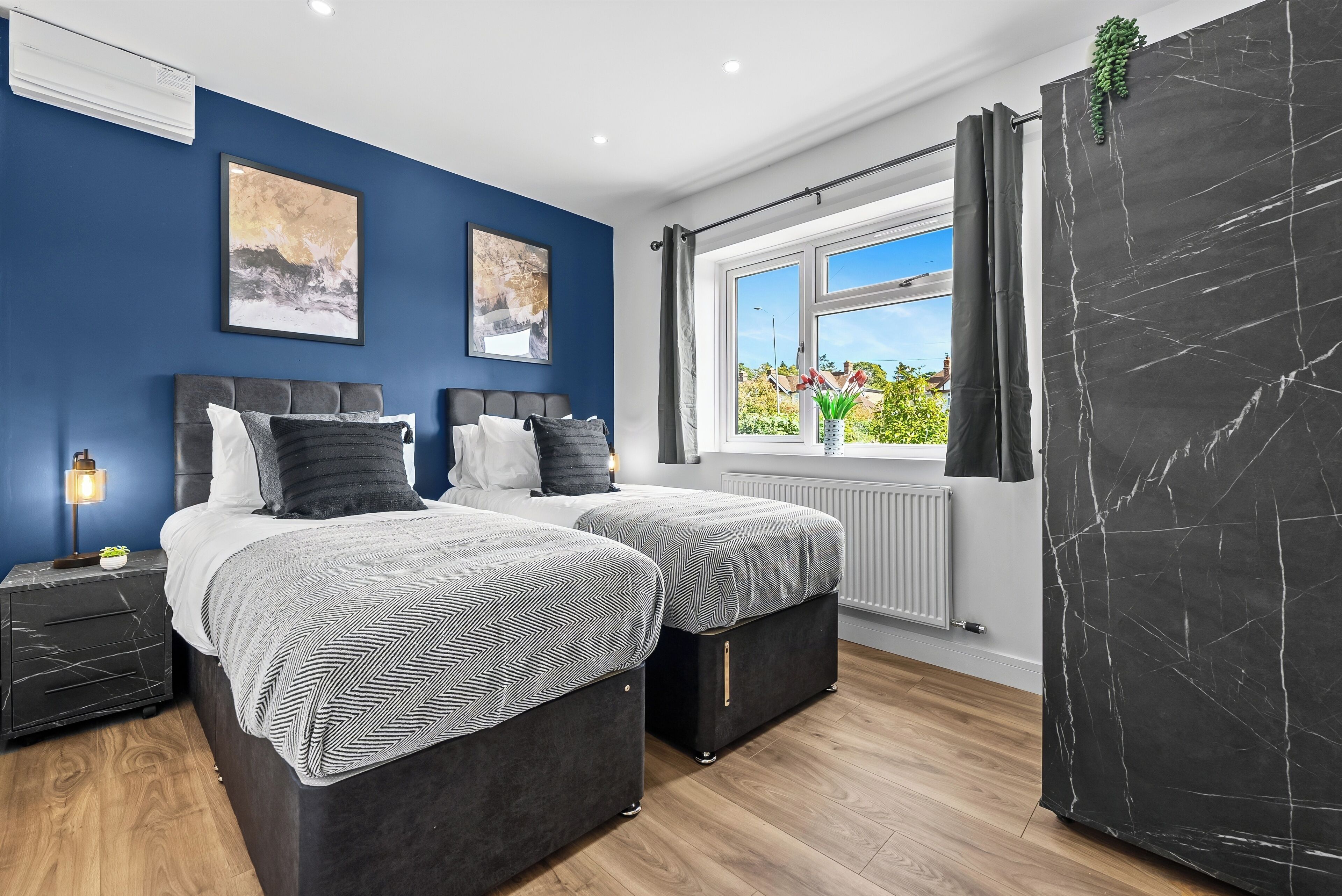 A bedroom with two beds, a window with a view, and a radiator.
