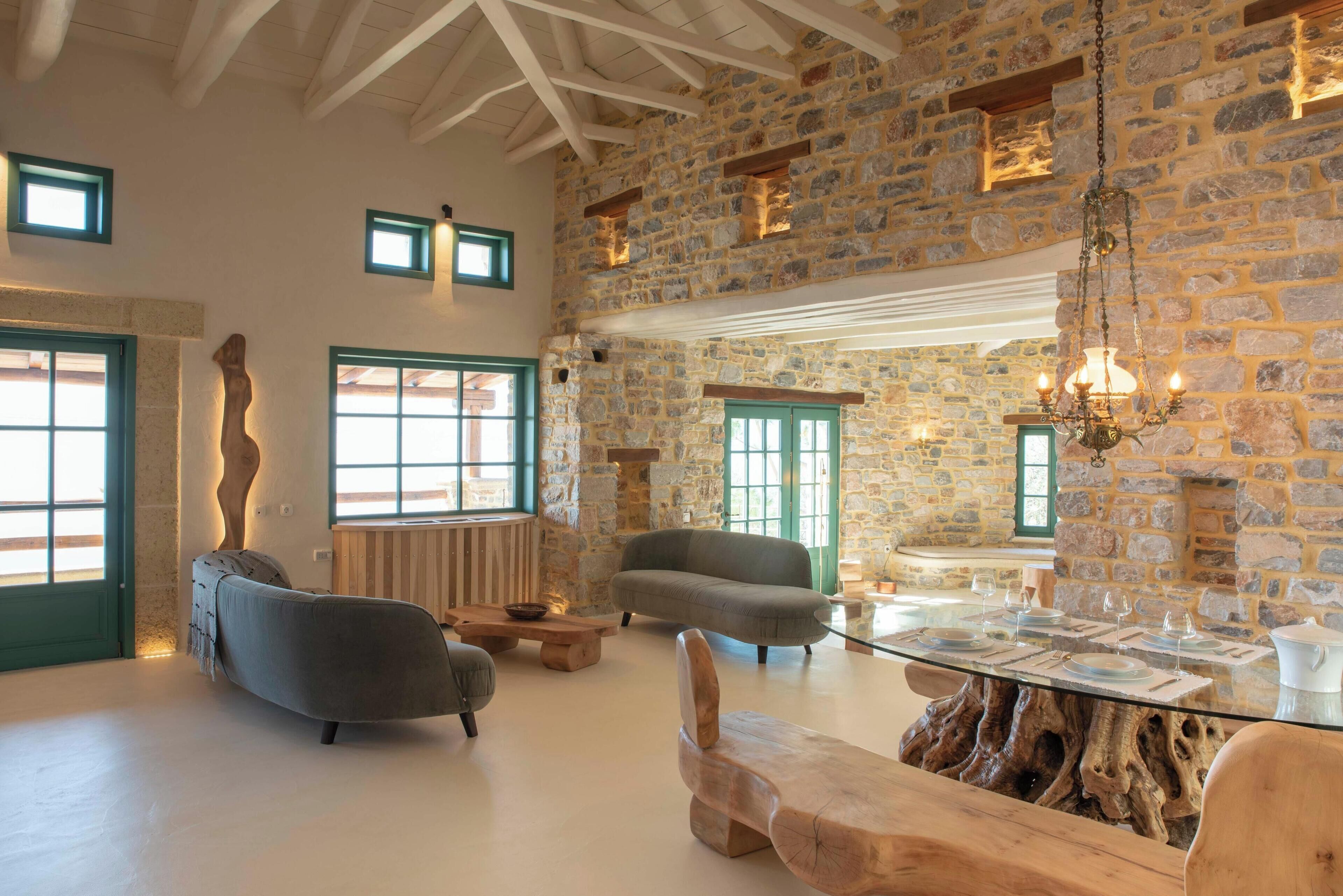 Una habitación amplia con una pared de piedra, una mesa de madera y dos sofás.