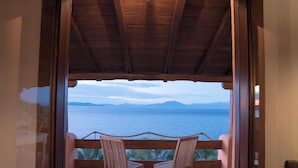A wooden balcony with two chairs facing a scenic view of the sea and mountains. - Cypresses Villas (South Pelion)