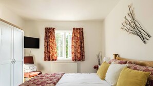A bedroom with a bed, a wardrobe, a television, and a window with curtains. - Cosy Annex, South Facing Patio (Falmouth)