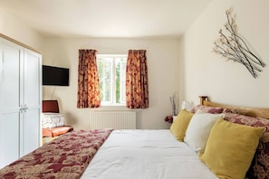 A bedroom with a bed, a wardrobe, a television, and a window with curtains. - Cosy Annex, South Facing Patio (Falmouth)
