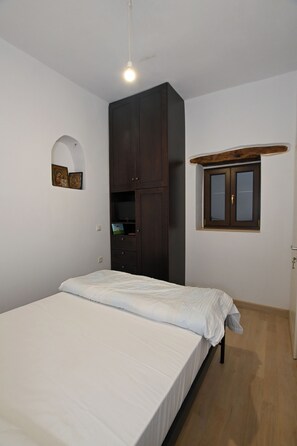 A bedroom with a bed, a wardrobe, a small window, and a light fixture. - Chania Hillside 2BD Home – Nature & Comfort by ΜΡS (Plemeniana)