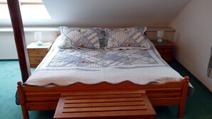 Een slaapkamer met een houten bed, een bankje, twee nachtkastjes en een raam.