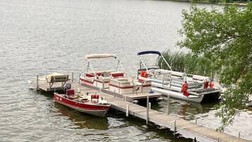 Un muelle con varias embarcaciones, incluyendo un motorboat rojo y blanco y un motorboat blanco con toldo azul.