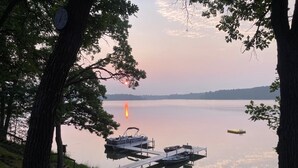 Un lago tranquillo con barche ormeggiate al molo, circondato da alberi.