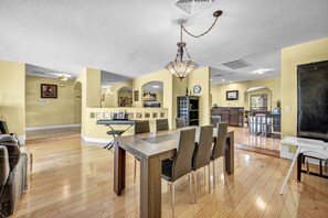 A spacious dining area with a long table, chairs, and a chandelier. - Family & Group Retreat with Pool, Spa & Basketball (Las Vegas)