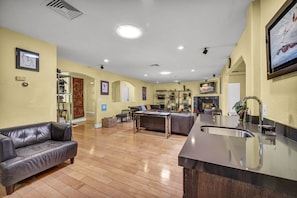 A spacious living area with a leather sofa, a dining table, and a kitchen with a sink. - Family & Group Retreat with Pool, Spa & Basketball (Las Vegas)