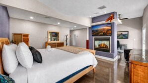 Ein modernes Hotelzimmer mit einem großen Bett, einem Kamin, einem Schreibtisch und einem Fernseher.
