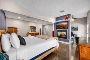 A modern hotel room with a large bed, a fireplace, a desk, and a television. - Family & Group Retreat with Pool, Spa & Basketball (Las Vegas)