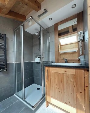 Ein modernes Badezimmer mit einer Duschkabine aus Glas, einem Holzwaschtisch und einem großen Spiegel.