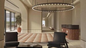 A spacious lobby with a large circular light fixture, two black armchairs, a coffee table, and a reception desk. - Safin Hotel & SPA (Orikum)
