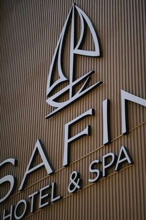 Une enseigne pour un hôtel et un centre de bien-être, avec un logo représentant un voilier stylisé.