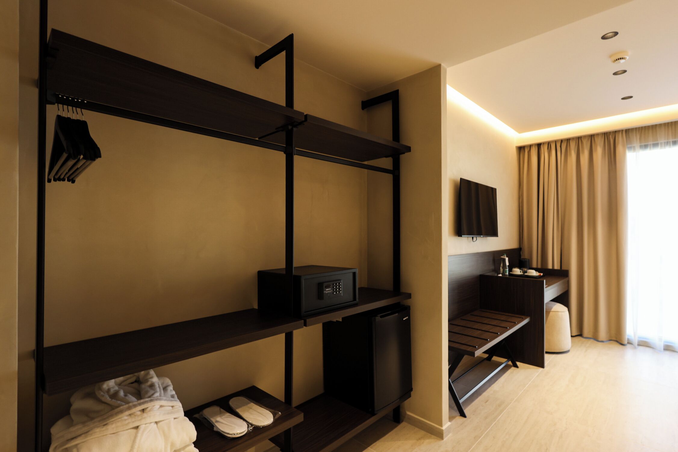 Ein Hotelzimmer mit einem Etagenbett, einem Schreibtisch mit Stuhl, einem an der Wand befestigten Fernseher und einem kleinen Kühlschrank.