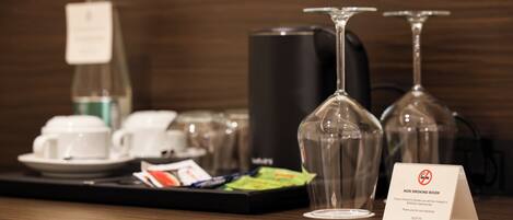A hotel reception area with a coffee station, wine glasses, and a non-smoking sign.