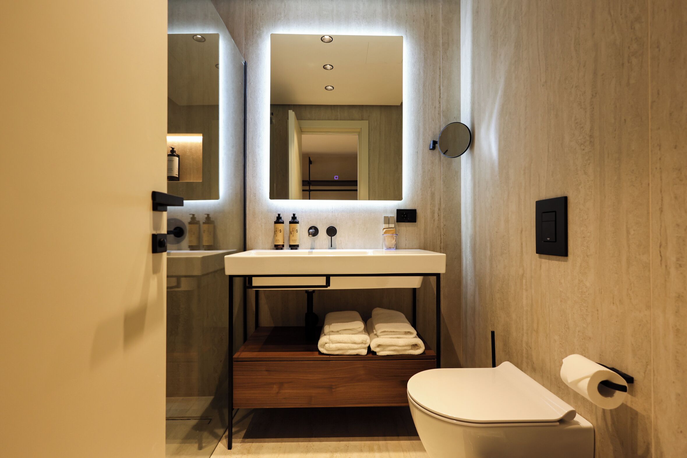 Un baño moderno con lavamanos integrado, un espejo, inodoro y toallero.