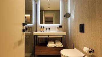 Un baño moderno con lavamanos integrado, un espejo, inodoro y toallero.