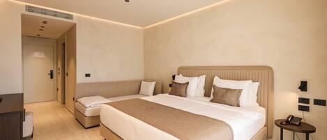 A modern hotel room with a large bed, a bedside table, a desk, and a chair.