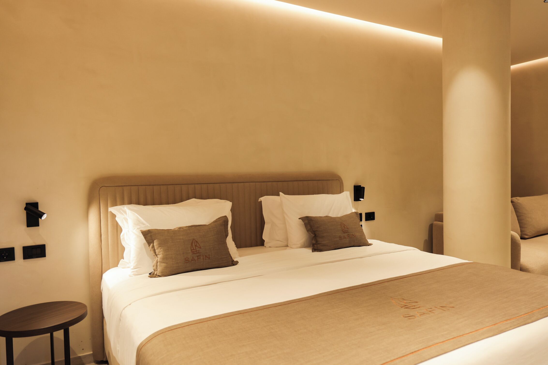 A hotel room with a large bed, two bedside tables, a round side table, and a wall-mounted lamp.