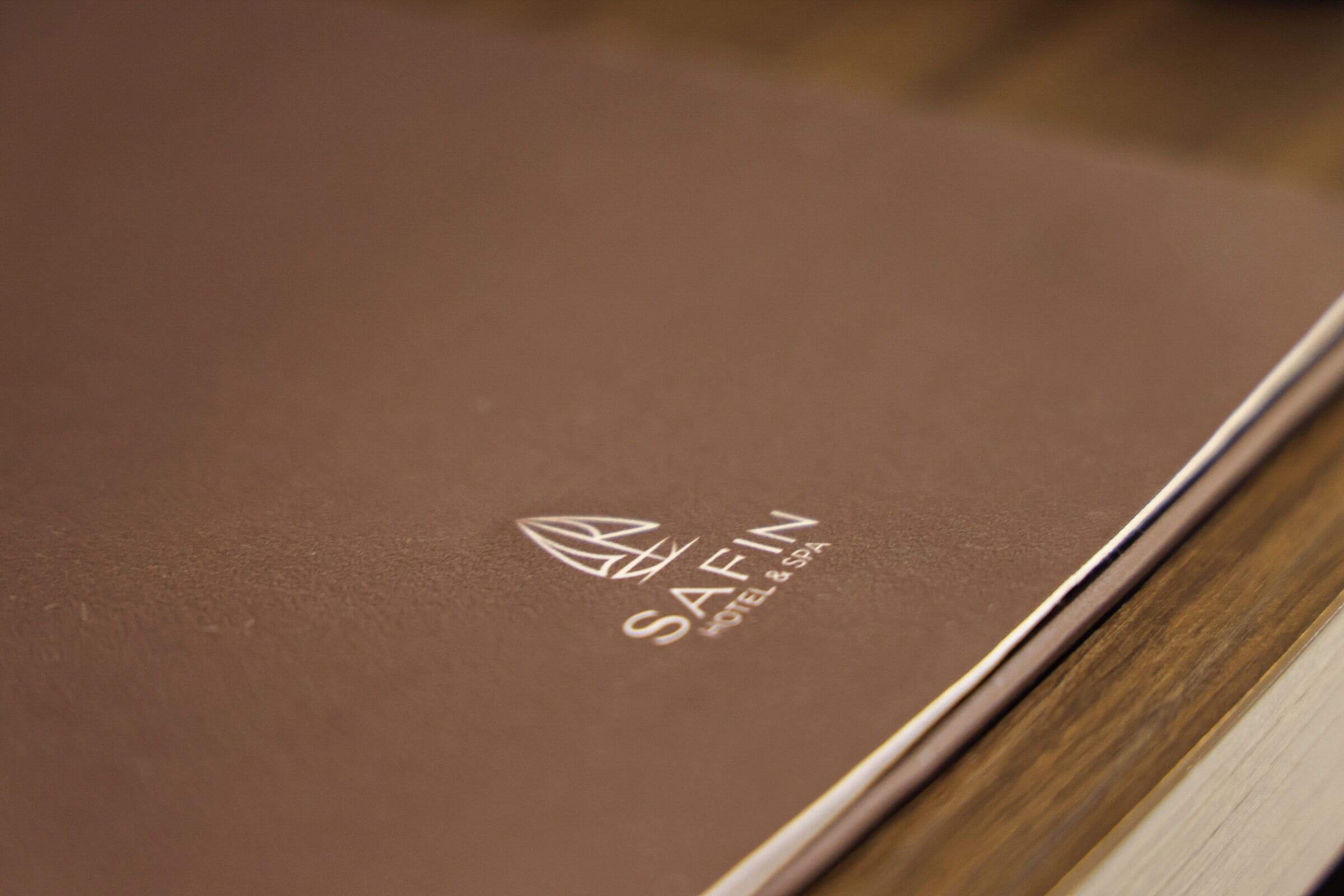 Ruskea, nahkakantisinen kirja, jonka kannessa on logo: ’SAFIN HOTEL & SPA’.