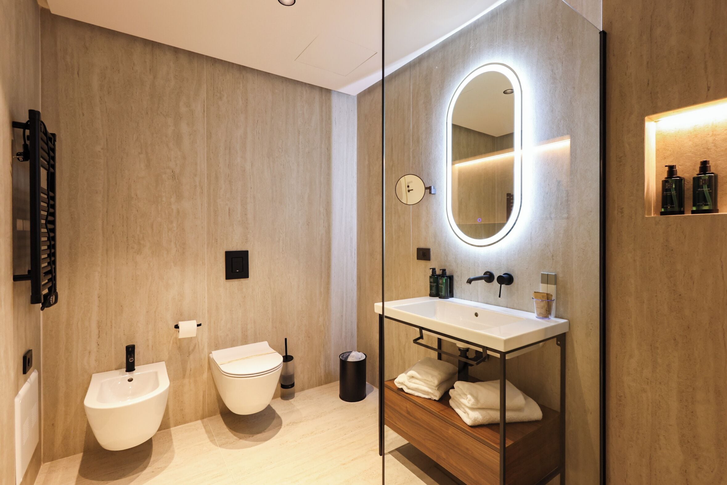 A modern bathroom with a wooden wall, a white sink with a mirror, and two white basins.