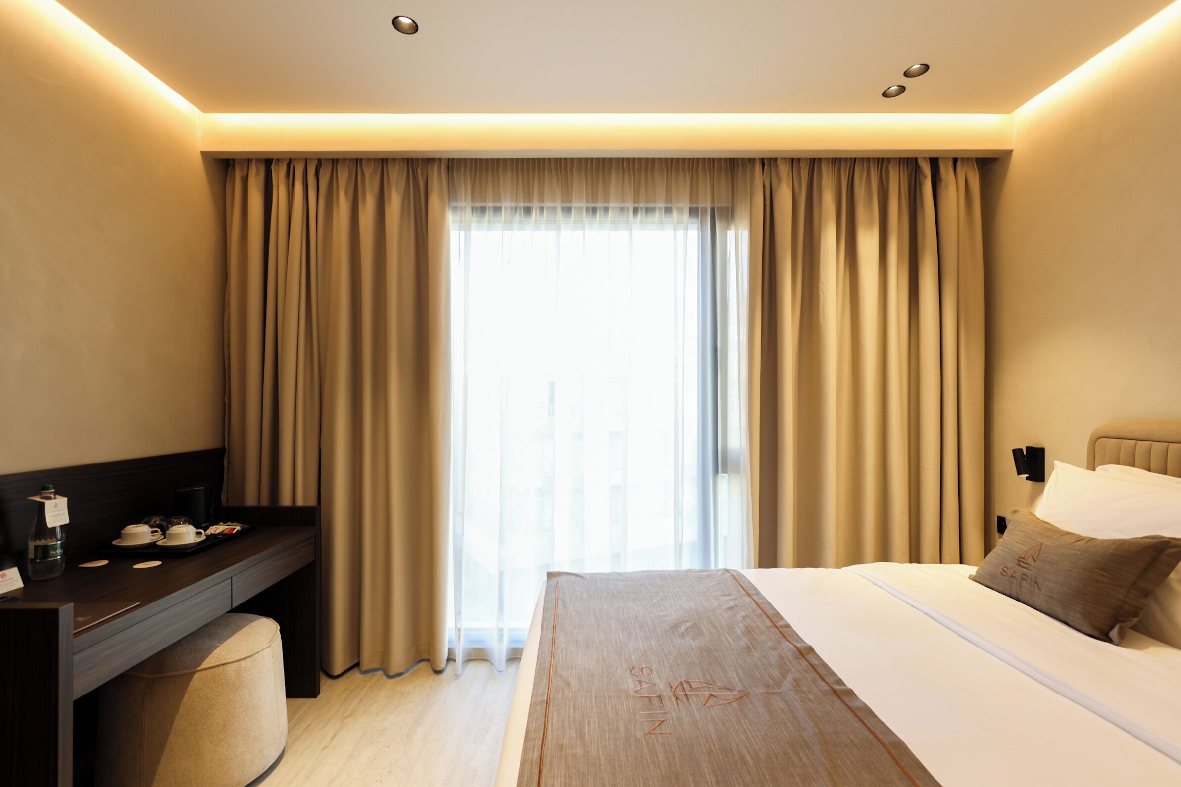 Ein Hotelzimmer mit Bett, Schreibtisch und einem fensterbepflanzten Fenster.