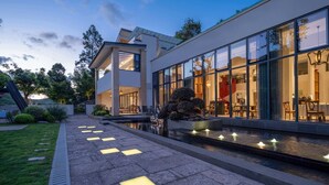 A modern house with large glass windows, a well-maintained garden, and a pathway leading to the entrance. - HeartLand Logde MoGanShan. (Huzhou)