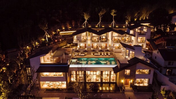A multi-story hotel with a pool, outdoor seating, and multiple balconies. - HeartLand Logde MoGanShan. (Huzhou)