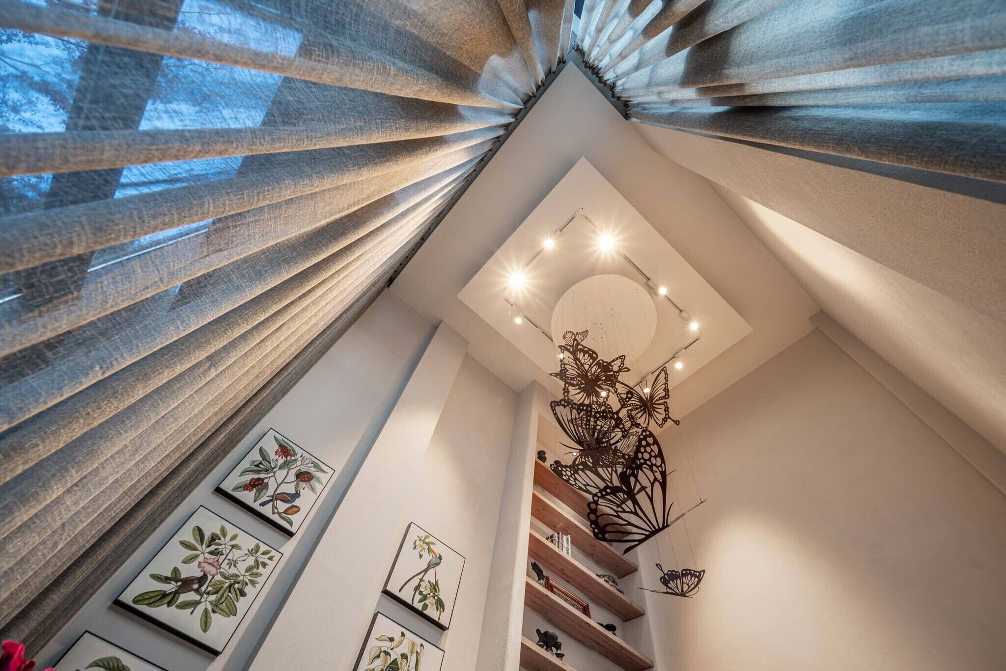 Un interior moderno con techo inclinado, iluminación empotrada y una escultura metálica decorativa.