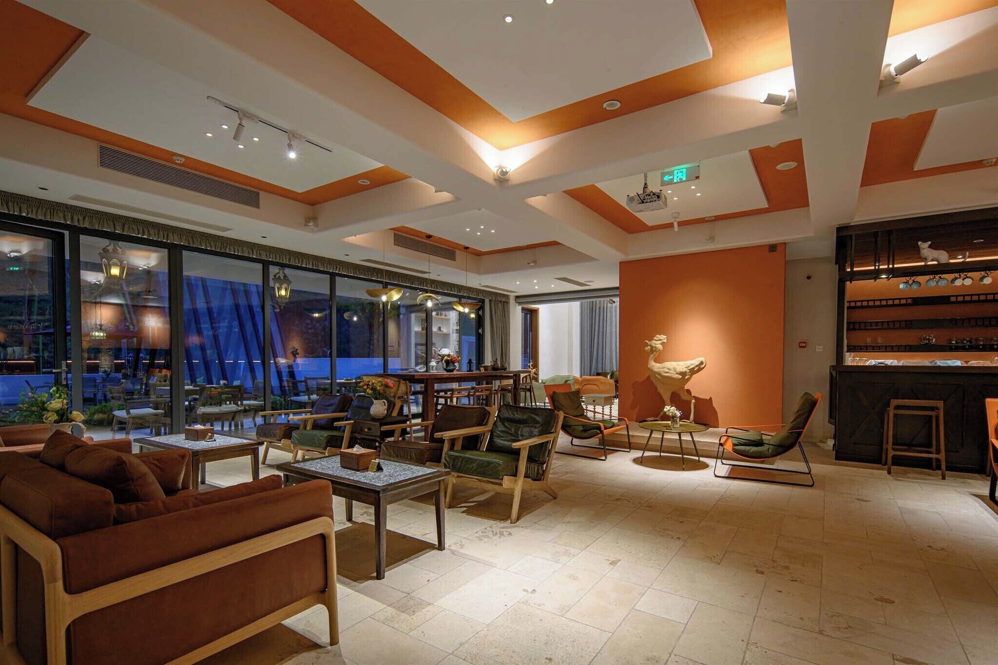 Un vestíbulo amplio con diseño moderno, que cuenta con diversas zonas de estar, un bar y grandes ventanales con vistas al exterior.