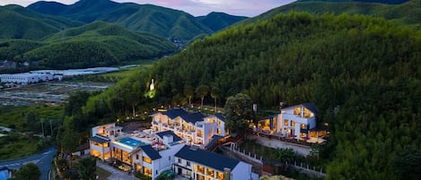 Una zona residencial moderna con varias casas de dos pisos, rodeada de abundante vegetación y colinas.