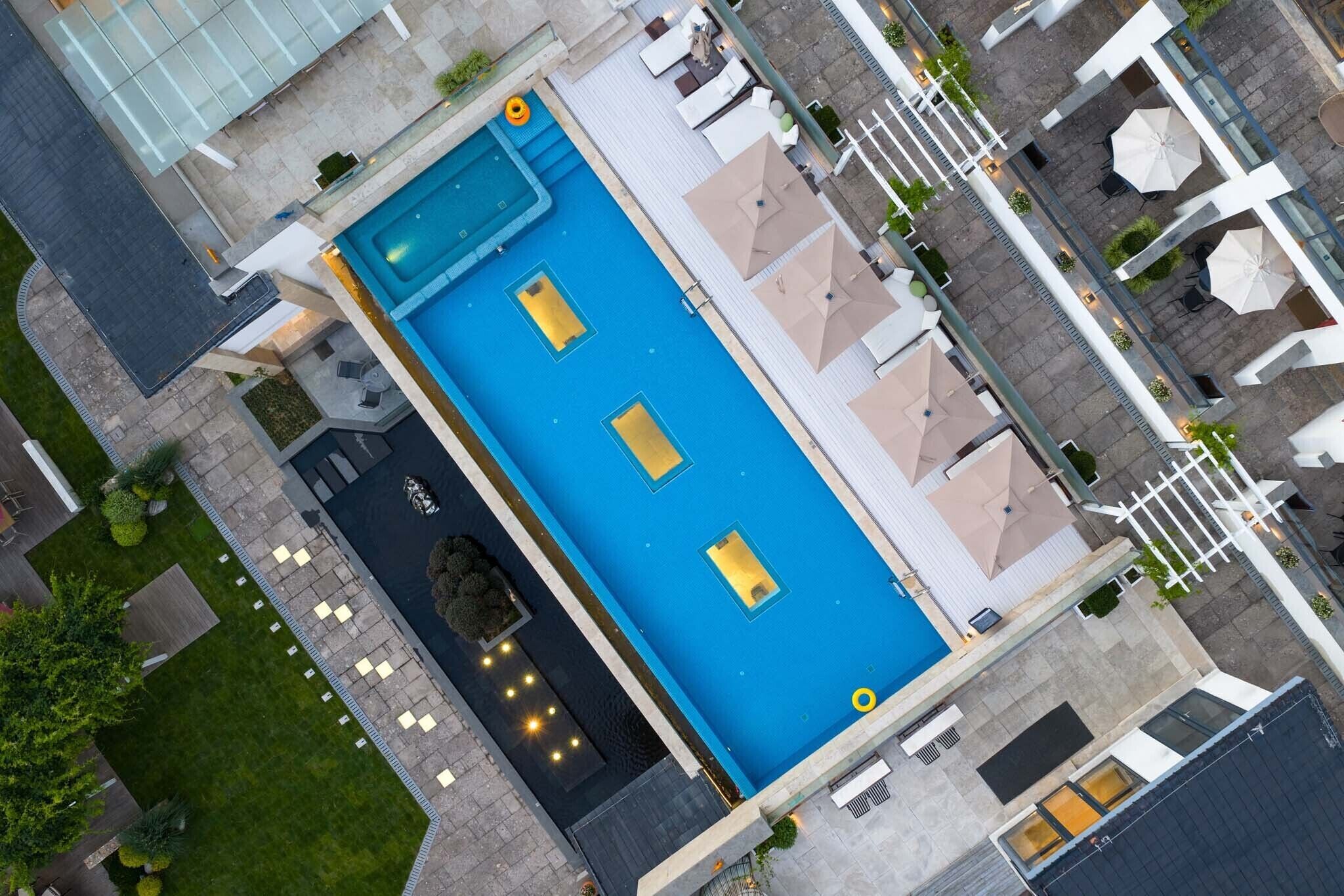Luchtbeeld van een hotel met een groot zwembad, buitenzitplaatsen en een verzorgde tuin.