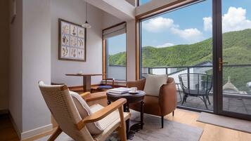 Una habitación moderna con un amplio ventanal corredero que da a un balcón con vistas panorámicas a colinas verdes.
