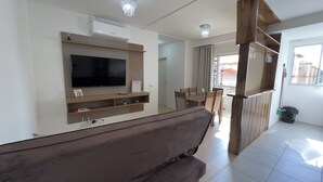 Un salon moderne doté d’un téléviseur à écran plat, de meubles en bois et d’un balcon offrant une vue agréable.