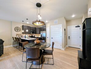 A modern kitchen with dark cabinets, a central island, and pendant lighting. - New Luxury | Keystone Lake | King Bed, Shuttle (Keystone)