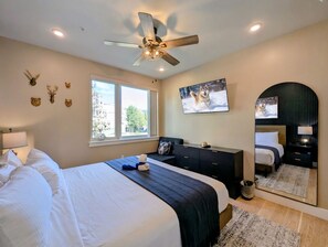 A bedroom with a bed, a dresser, a mirror, a ceiling fan, and wall decorations. - New Luxury | Keystone Lake | King Bed, Shuttle (Keystone)