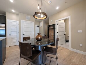 A dining area with a round table, four chairs, a vase, and a pendant light. - New Luxury | Keystone Lake | King Bed (Keystone)