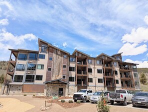 A multi-story residential building with balconies, a parking lot, and a clear sky. - New Luxury | Keystone Lake | King Bed, Shuttle (Keystone)
