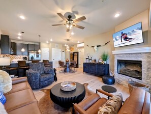 A spacious living room with a fireplace, a ceiling fan, and a television mounted on the wall. - New Luxury | Keystone Lake | King Bed, Shuttle (Keystone)