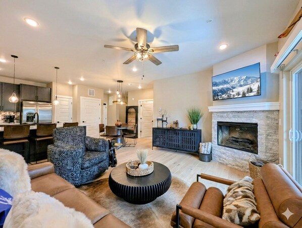 A spacious living room with a fireplace, a dining area, and a kitchen. - New Luxury | Keystone Lake | King Bed (Keystone)