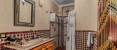 A bathroom with a shower, a sink with a mirror, and a towel rack.