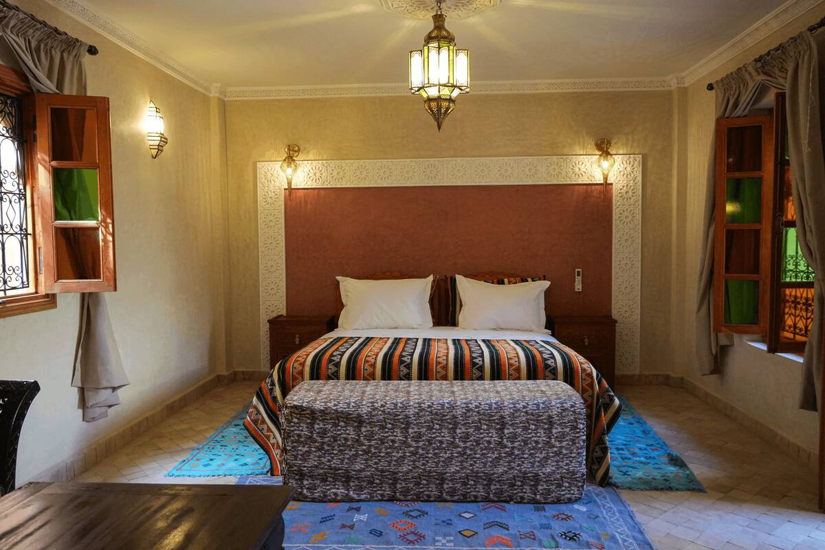 Una camera da letto con un letto grande, due comodini, un lampadario e tappeti decorati.