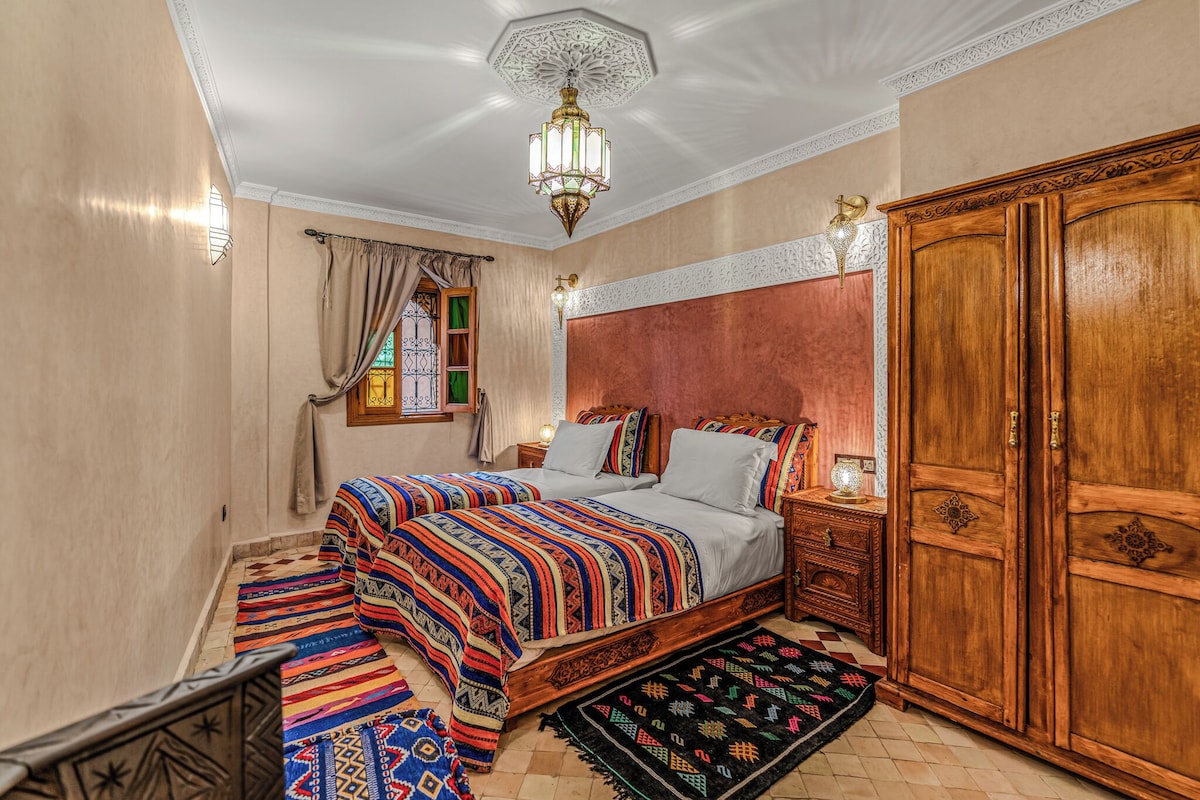 A traditional bedroom with a bed, wooden wardrobe, and a decorative ceiling light.