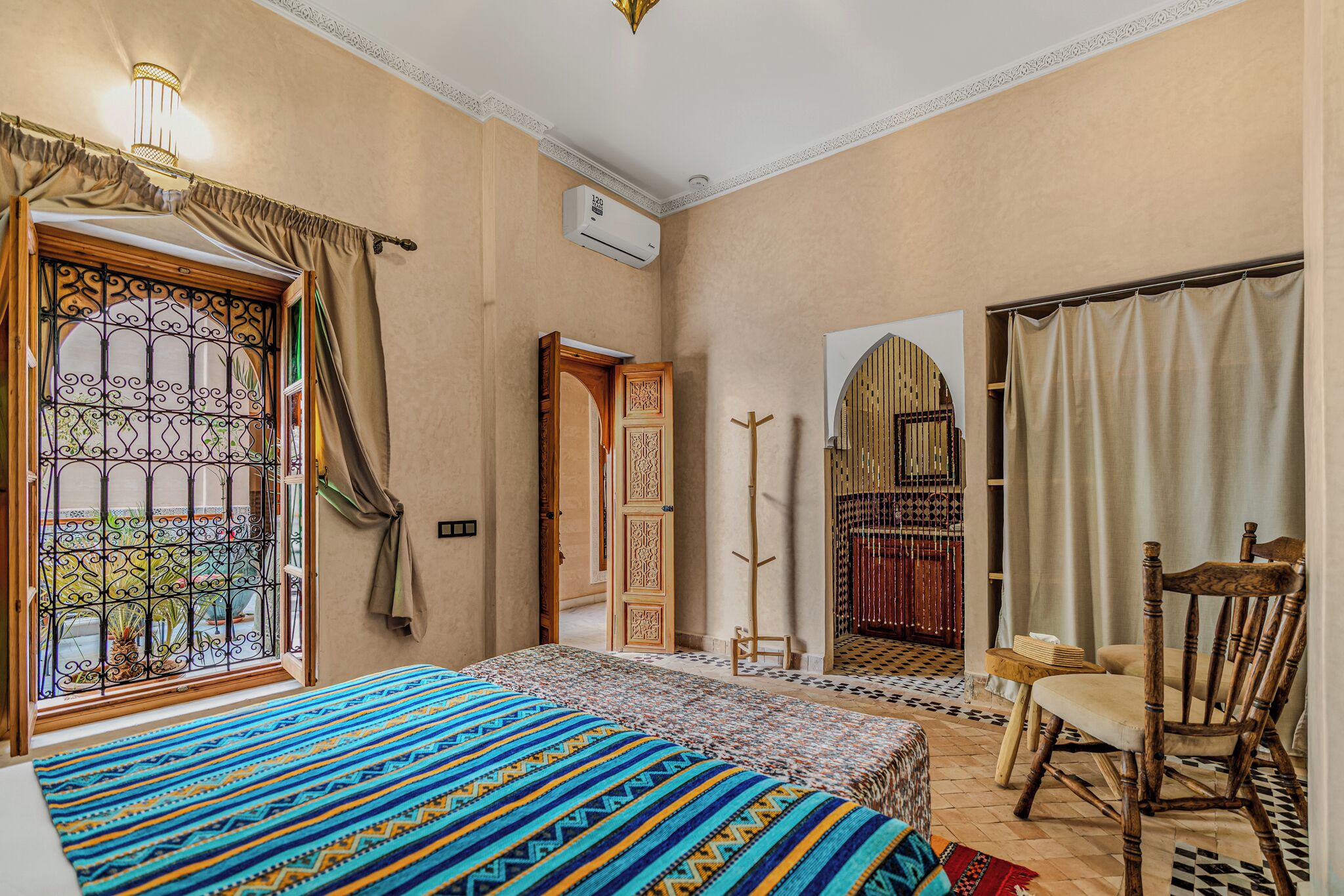 A bedroom with a bed, a chair, a wardrobe, and a window with curtains.