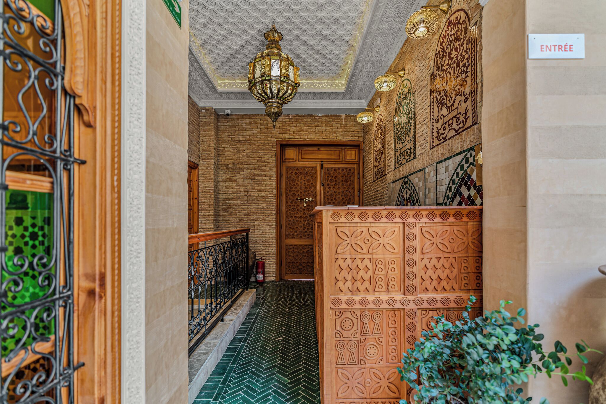 A hallway with a patterned floor, a wooden door, and a sign indicating the entrance.