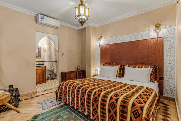 A hotel room with a large bed, a chandelier, a decorative wall panel, and a patterned rug. - Riad Maison D'HÔTE ABDEL & JAMILA (Marrakech)