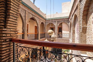 Une cour bordée de murs en briques, agrémentée d’arches et illuminée par des lampes suspendues.