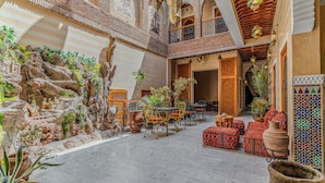 A courtyard with a rock garden, seating area, and traditional decor. - Riad Maison D'HÔTE ABDEL & JAMILA (Marrakech)